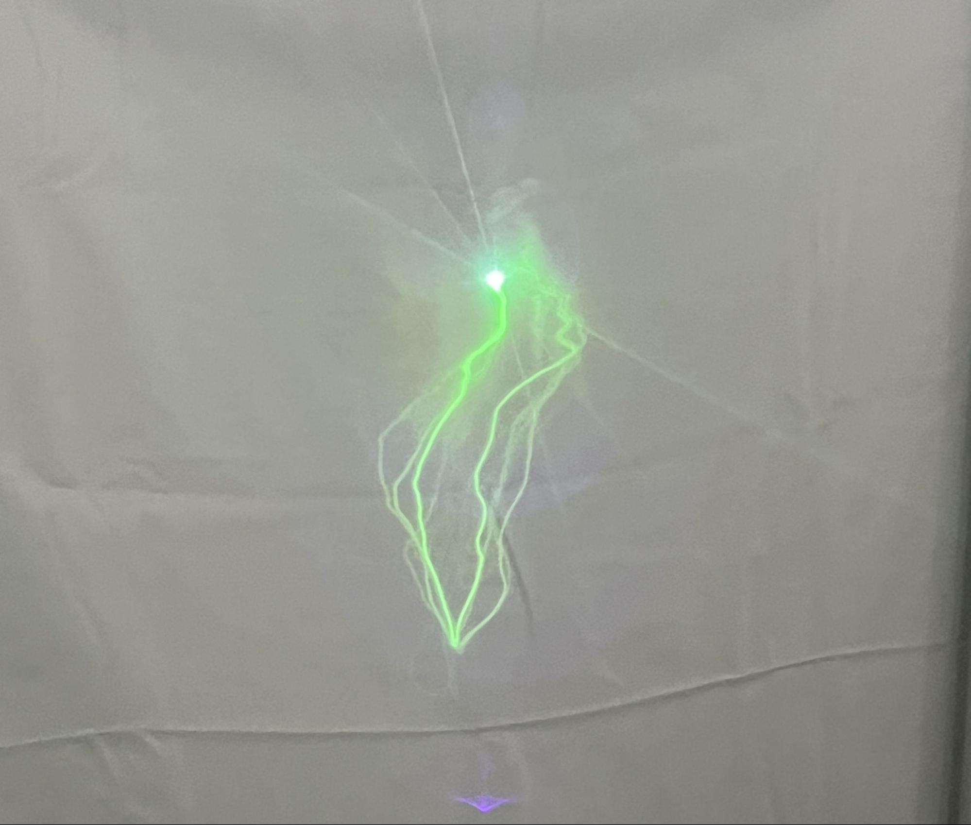A looping glowing line on a hanging phosphorescent sail, drawn by a stationary laser as the sail moved