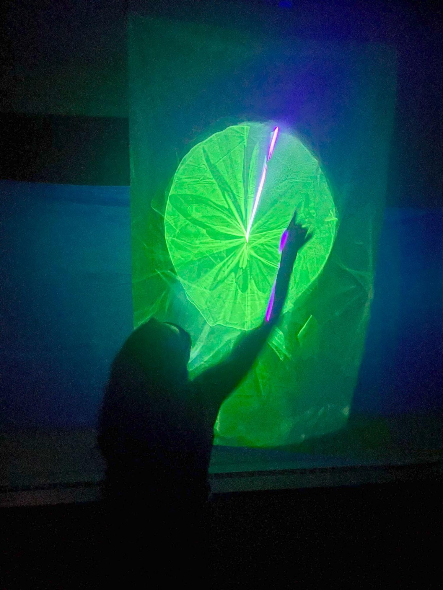 A dense moiré pattern of overlapping glowing lines on the sail, with a hand touching the fabric