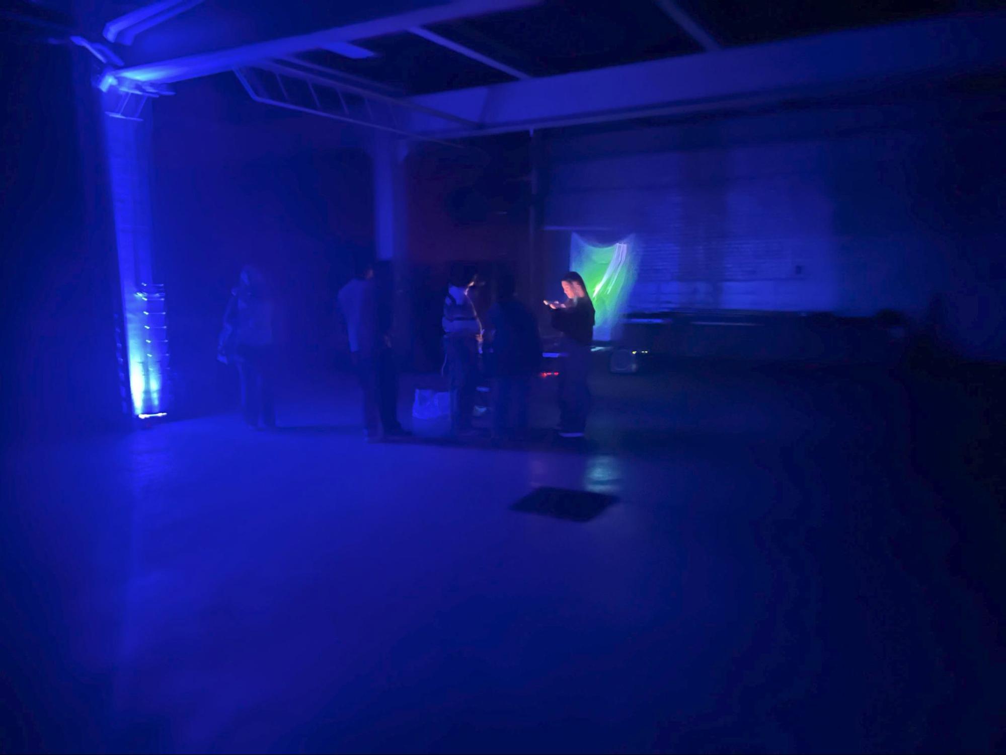 The exhibition room in low blue light, with the glowing sail visible at the far end